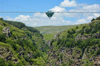 The Diamond Eye glass suspension bridge hanging over the lush green Dashbashi Canyon in Georgia, featuring a diamond-shaped panoramic platform