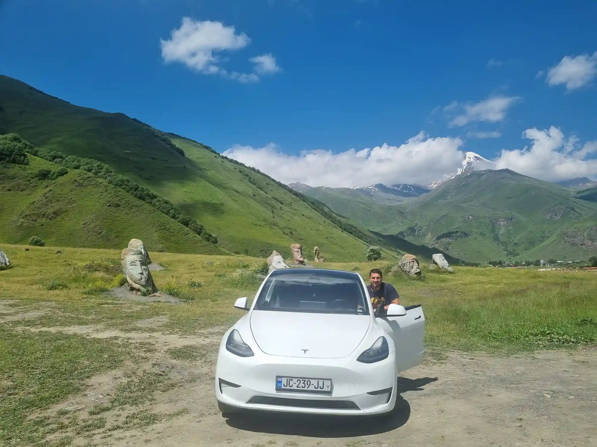 Tesla Model Y electric tour vehicle parked against a wide mountain backdrop during a private day trip in Georgia