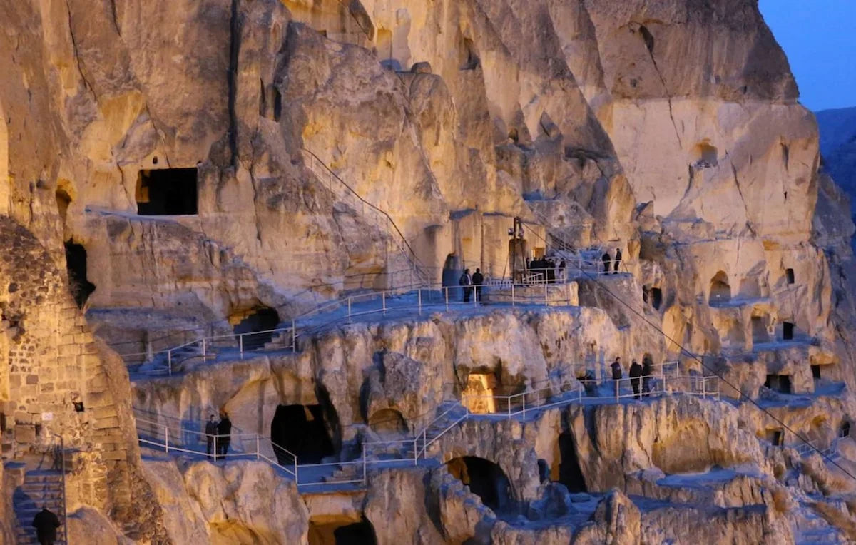 Historic Vardzia cave monastery complex in Georgia illuminated at night, showing ancient rock-cut dwellings and tunnels on Erusheti Mountain